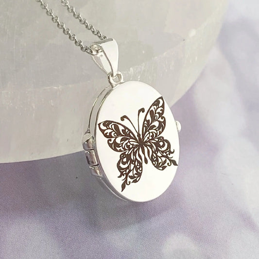 Silver locket with butterfly design on a soft fabric background
