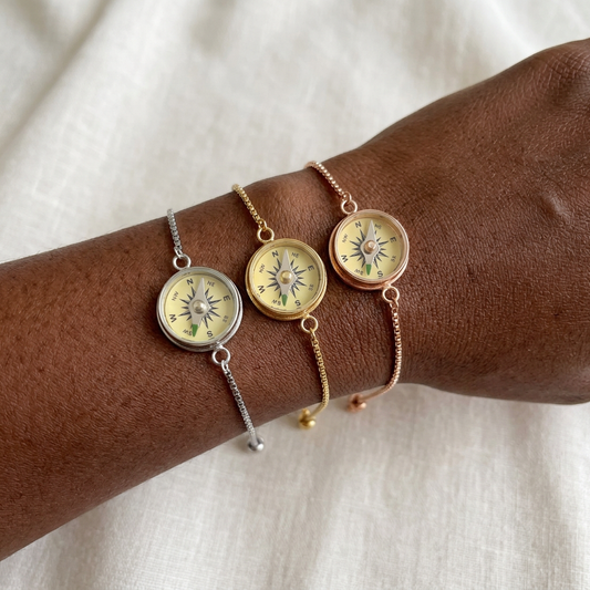 Silver, gold, and rose gold Working Compass Bracelets on a darker-skinned woman's wrist